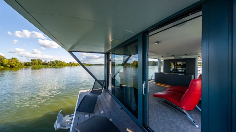 Blick an der Glasfront des Hausboots entlang auf den See am Morgen