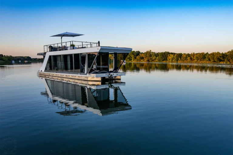 Hausboot mit Dachterrasse auf spiegelglattem See im Abendlicht