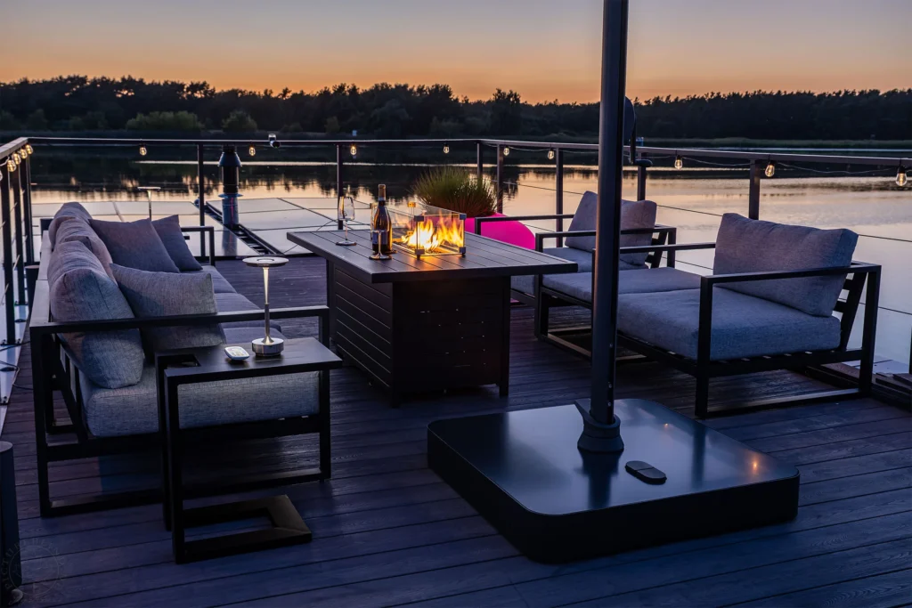 Terrasse am Abend mit Feuertisch und Lounge-Möbeln über dem Wasser