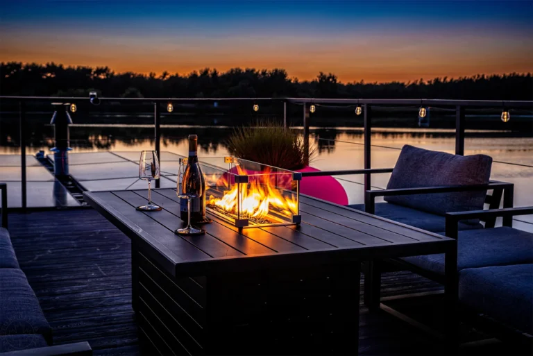 Feuertisch mit Champagner auf der Terrasse bei Sonnenuntergang am See