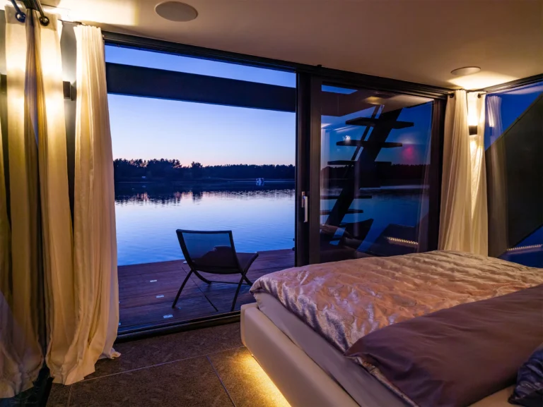 Blick aus dem Schlafzimmer durch die offene Schiebetür auf den See in der Dämmerung