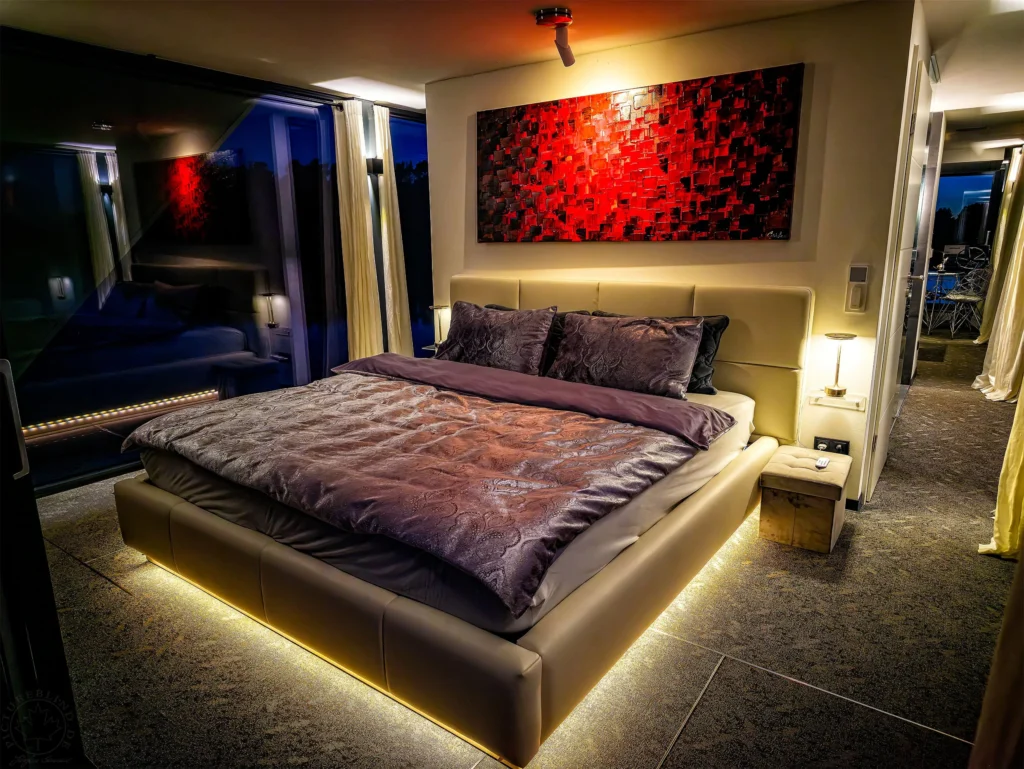 Schlafzimmer im Hausboot bei Nacht: Doppelbett mit indirekter Beleuchtung und rotem Wandbild