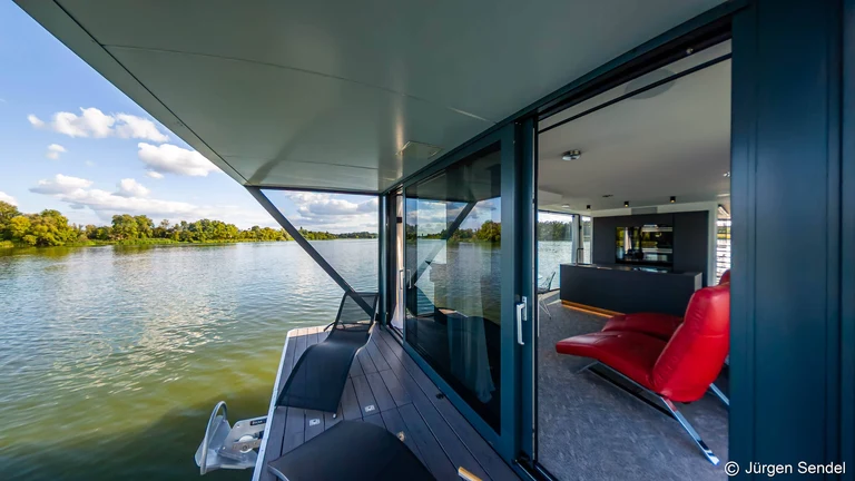 Blick an der Glasfront des Hausboots entlang auf den See am Morgen